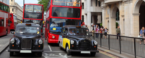 Red double-deckers with tourists and taxi on street of London, E
