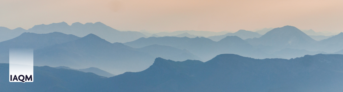 Misty mountains in the distance with the IAQM logo in the bottom left corner