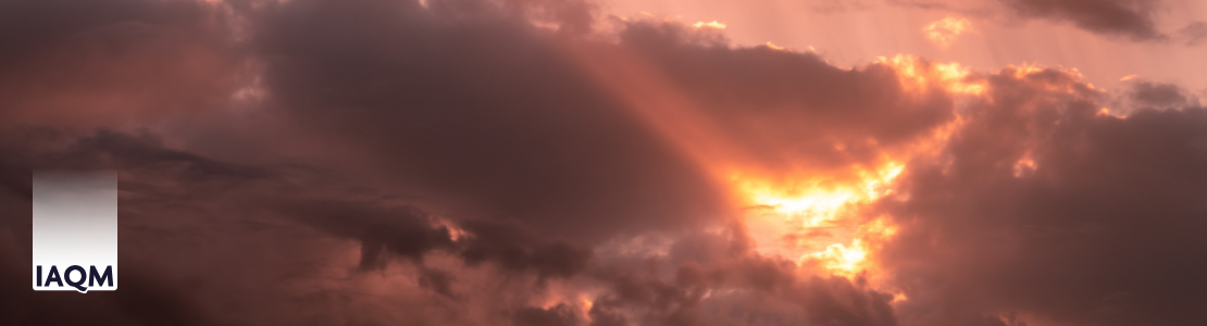 Clouds at sunset coloured orange and red with the sun shining through. The IAQM logo is visible.